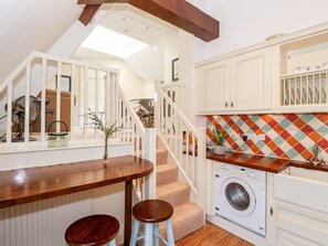 Una cocina con mostrador de madera, lavadora y escalera.