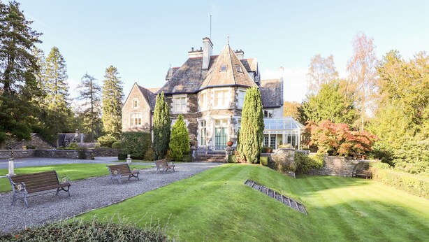 A well-maintained garden with a lawn, benches, and a stone wall. - Loughrigg Suite (Ambleside)