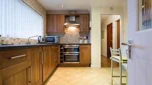 Una cocina con armarios de madera, un microondas y dos hornos.