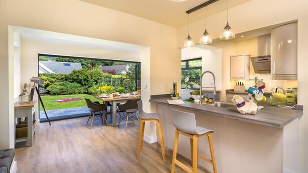 A modern kitchen with a large window, a dining area with two chairs, and a small island with a sink. - Greengarth (Keswick)