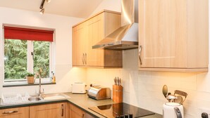 Una cocina moderna con armarios de madera, campana de acero inoxidable, horno empotrado, tostadora y hervidor.