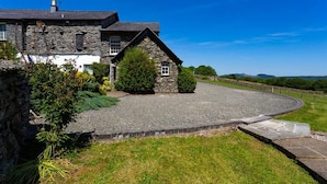 A stone house with a gravel driveway and a stone pathway leading to the entrance.