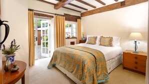 A bedroom with a bed, bedside table, lamp, and a view through an open door.