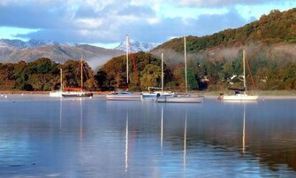 A calm lake with several sailboats anchored.