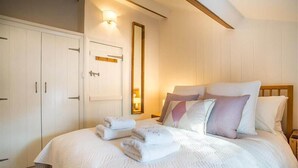 Un dormitorio con cama, almohadas, una mesita de noche, un espejo y un armario.