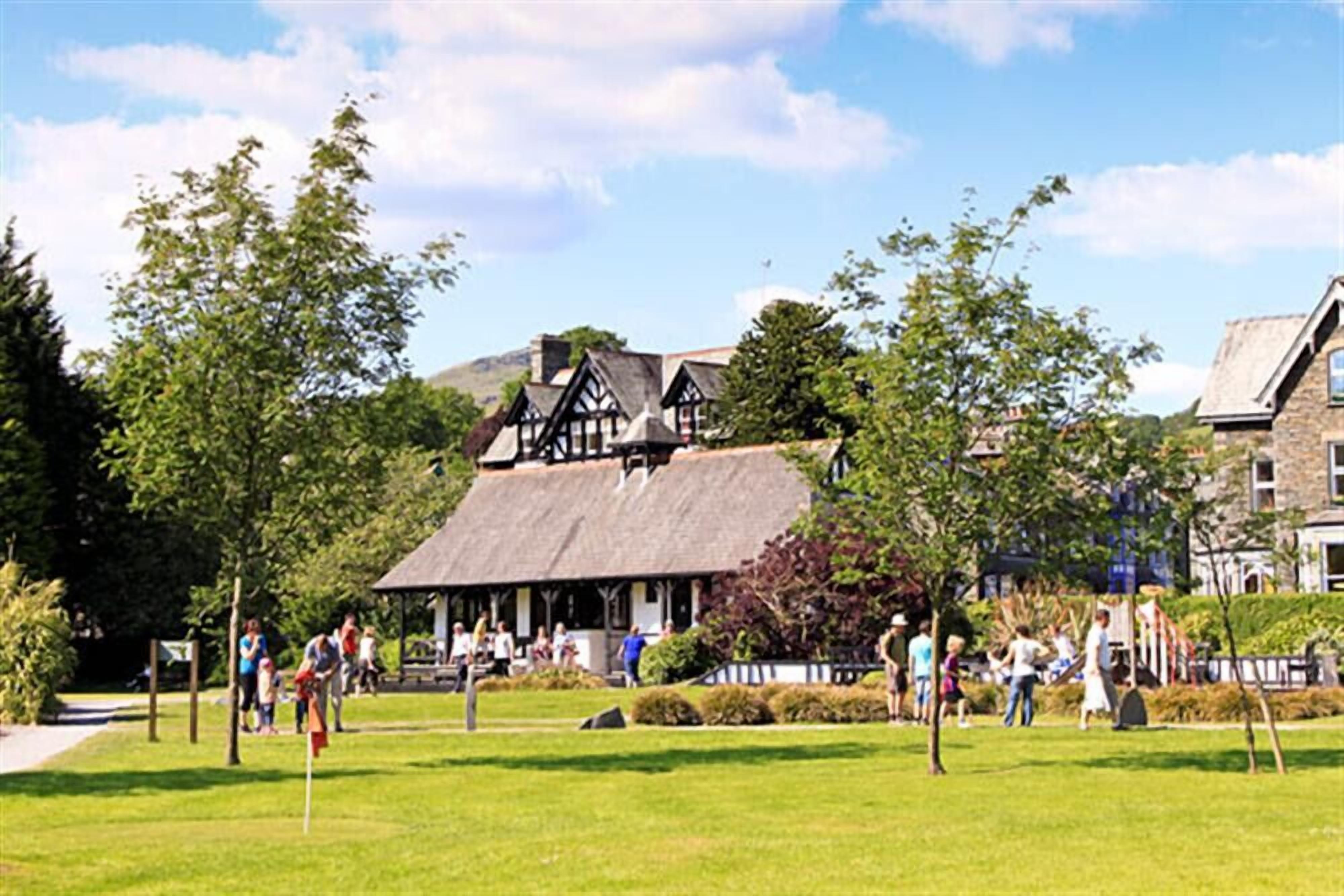 A traditional building with a thatched roof, surrounded by a well-maintained lawn and trees.