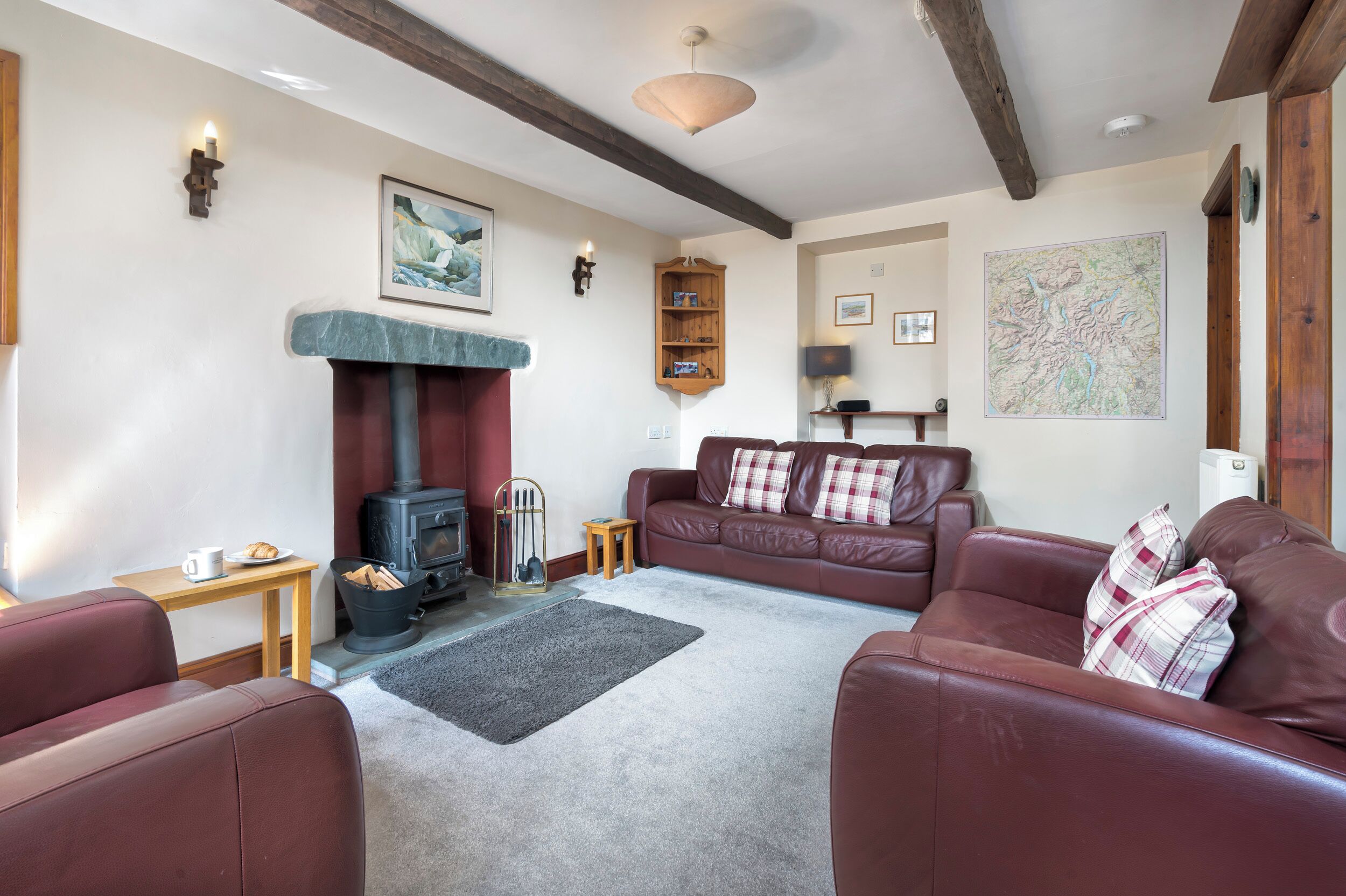 A cozy living room with a fireplace, leather sofas, a small table with a cup and plate, and a map on the wall.