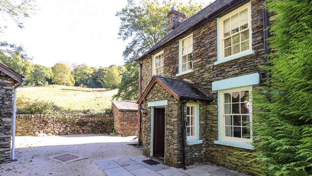 A stone house with a gravel driveway and a grassy lawn. - Jessicas Cottage (Windermere)