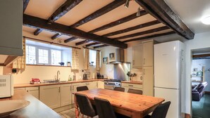 Une cuisine avec une table et des chaises en bois, une cuisinière et un réfrigérateur.