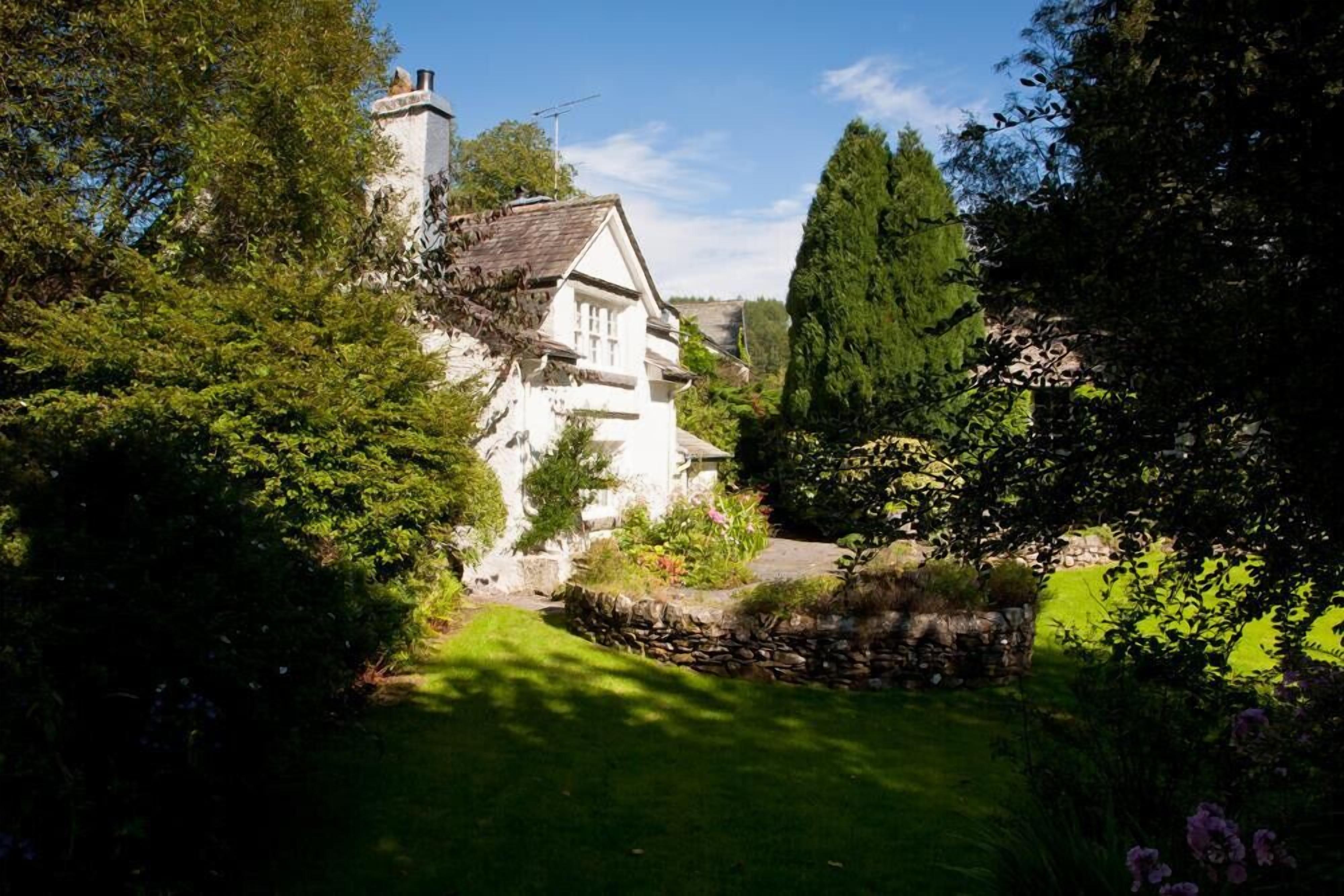 Une maison blanche avec un mur en pierre et un jardin.