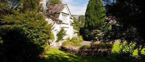 Une maison blanche avec un mur en pierre et un jardin.