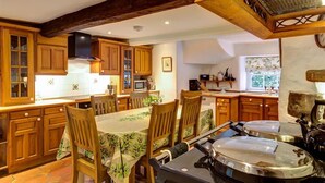 Una cocina con armarios de madera, una mesa de comedor con sillas y una estufa.