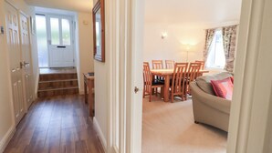 A hallway leading to a dining area with a table and chairs, a staircase, and a sofa in a living room. - Mardale (Ambleside)