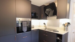 A modern kitchen with dark cabinetry, a microwave, oven, and a stainless steel sink. - Mardale (Ambleside)