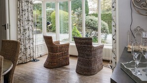 Une pièce dotée d’une baie vitrée, de fauteuils en osier, d’une table et d’un radiateur.