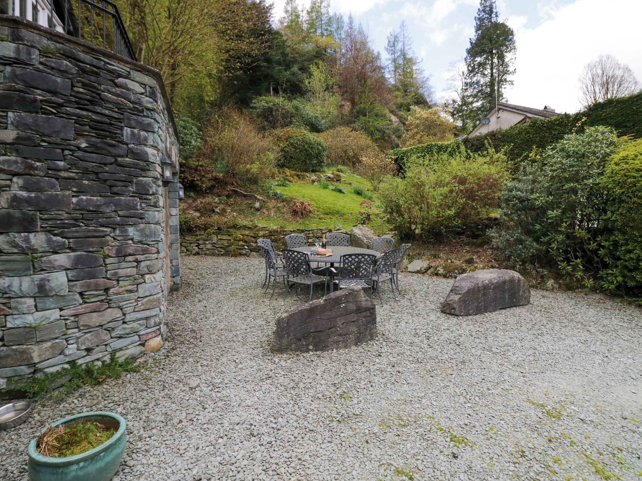 A stone building with a gravel patio, outdoor seating, and surrounding greenery.