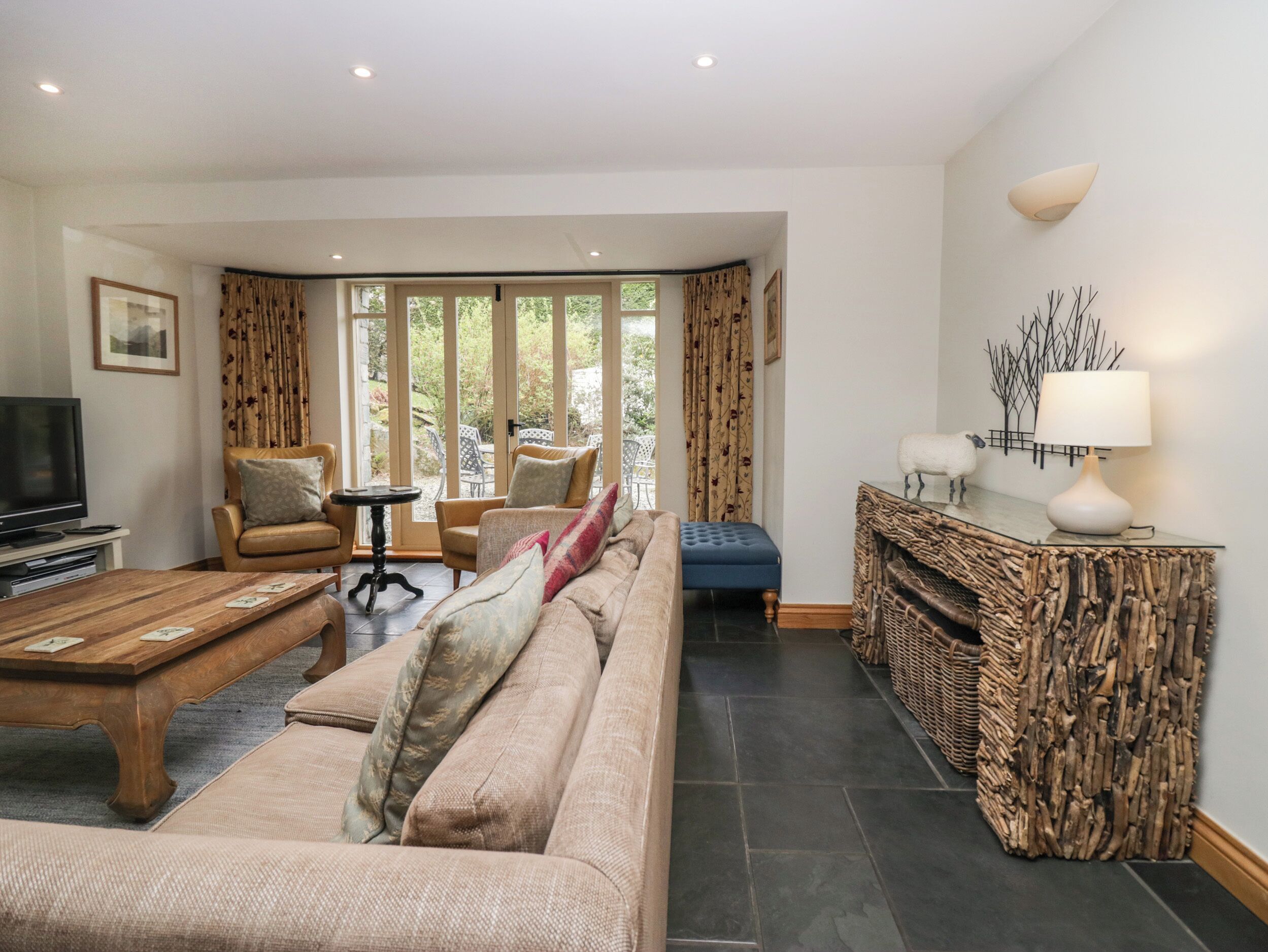 A living room with a sofa, armchairs, a coffee table, a TV, and a fireplace.