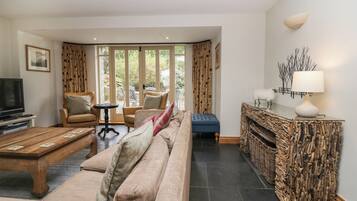 A living room with a sofa, armchairs, a coffee table, a TV, and a fireplace.