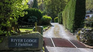 Une plaque en pierre portant l’inscription « RIVER LODGE 3 Fieldfoot », indiquant le nom et l’emplacement de la propriété.