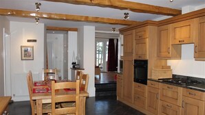 Una cucina con mobili in legno, un tavolo da pranzo con sedie e un piano cottura.
