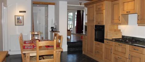 A kitchen with wooden cabinets, a dining table with chairs, and a stove.
