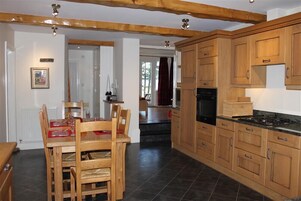 A kitchen with wooden cabinets, a dining table with chairs, and a stove.