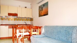 Ein gemütlicher Wohnbereich mit Küchenzeile, einem Essbereich mit Holzkreisl und einem hellblauen Sofa.