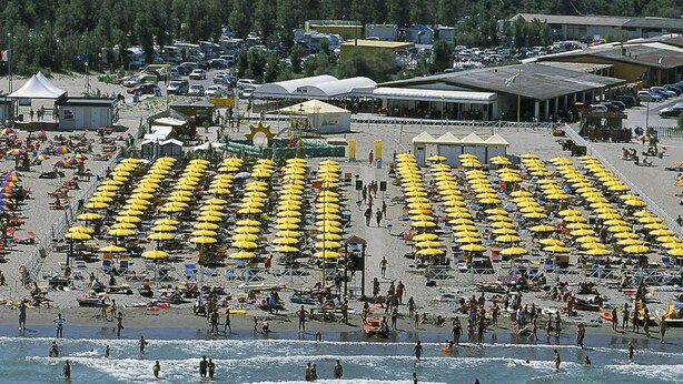 A beach with rows of yellow umbrellas and people swimming in the water. - Cosy apartment for 5 people with WIFI, A/C, pool, TV, patio and pets allowed (Rosolina)