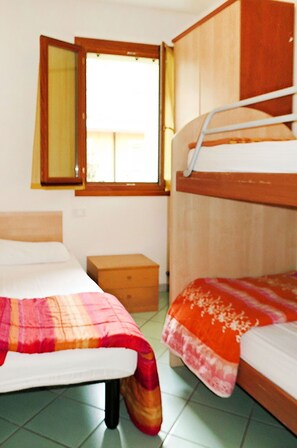 Une chambre avec deux lits, une tête de lit en bois, une table de chevet et une fenêtre avec des rideaux.