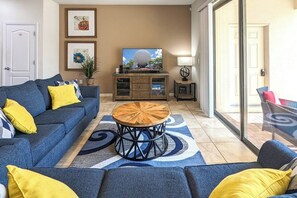A living room with a blue sofa, a coffee table, and a television.