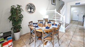 A dining area with a round wooden table, six chairs, and a potted plant.