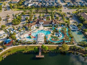 Ein Luftbild eines Resorts mit einem zentralen Pool, einer Wasserrutsche und einer Anlegestelle, die in einen See führt.