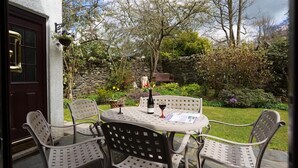 An outdoor patio with a round table and four chairs, a bottle of wine, and a menu. - Fairhaven (Windermere)