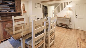 Ein Essbereich mit Holztisch und Stühlen, einem Teppich und einer Treppe, die in einen anderen Raum führt.
