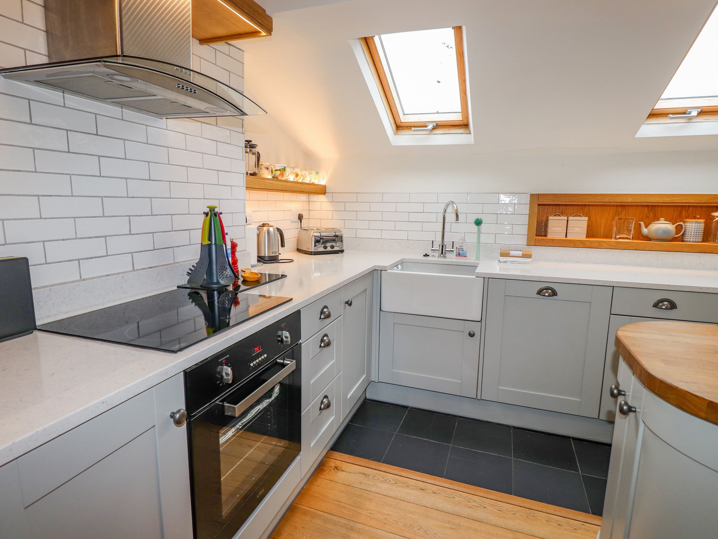A modern kitchen with white cabinetry, a built-in oven, a sink, and a skylight.