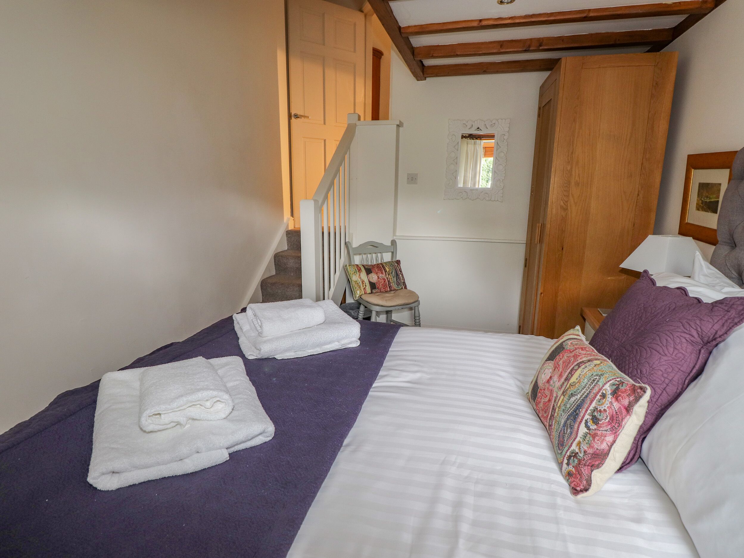 Ein Schlafzimmer mit einem Bett, zwei Handtüchern, einem Sessel, einem kleinen Tisch und einer Treppe.