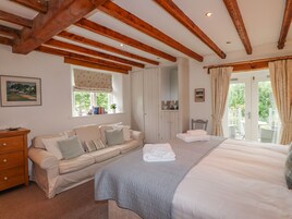 Un dormitorio acogedor con cama, sofá, cómoda y ventana con cortinas.