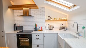 A modern kitchen with white cabinetry, a built-in oven, a toaster, and a sink. - Glen View Cottage (Ambleside)