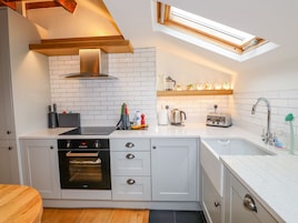Una cocina moderna con armarios blancos, horno empotrado, tostadora y tragaluz.