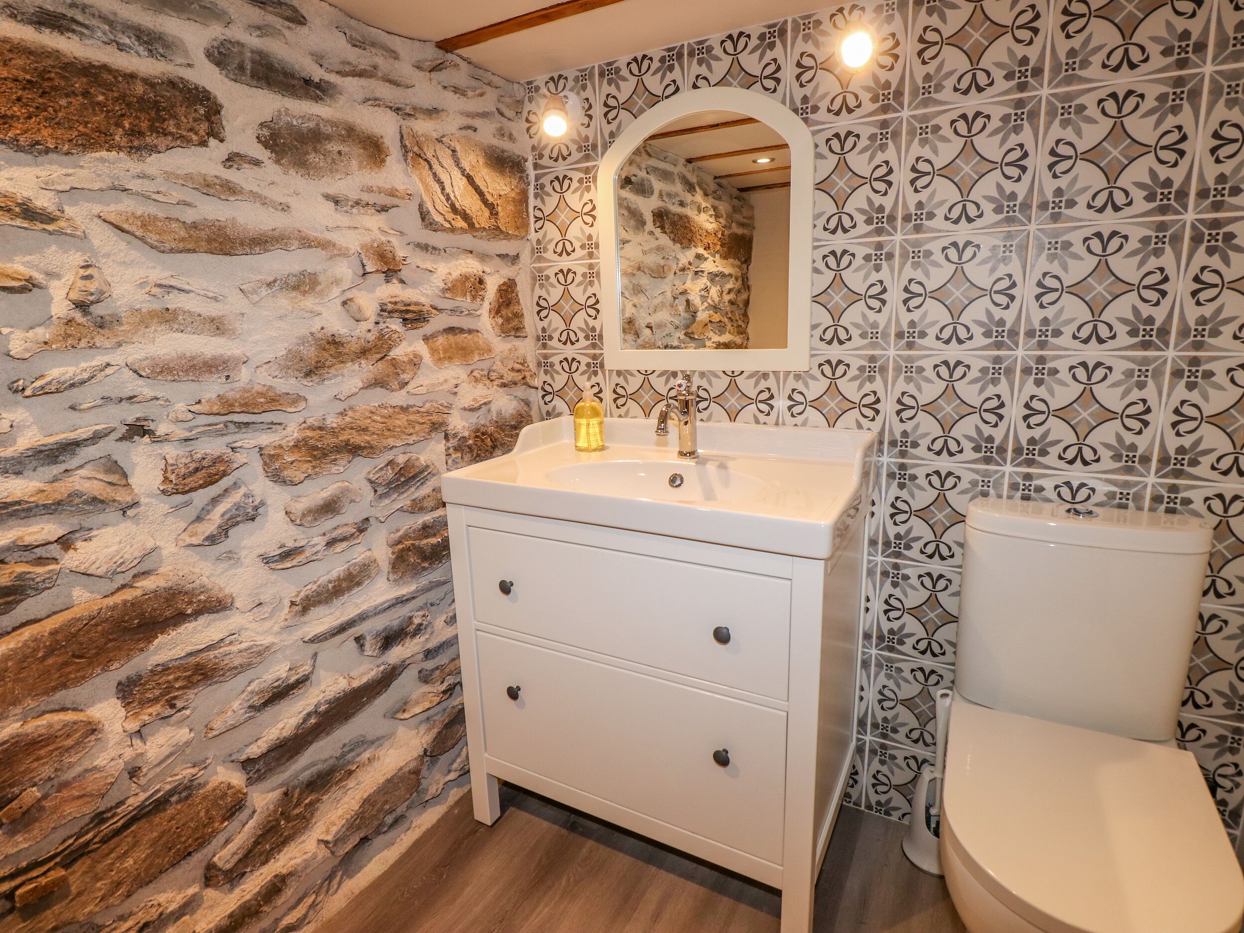 Ein Badezimmer mit Steinwand, Waschbecken und Toilette.