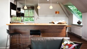 A modern kitchen with a wooden countertop, bar stools, and pendant lighting. - Harrison Stickle (Windermere)