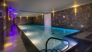 A modern indoor swimming pool with stone walls and ambient lighting. - Harrison Stickle (Windermere)