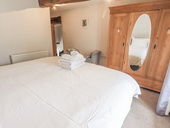 Un dormitorio con una cama grande, un armario de madera y un espejo.
