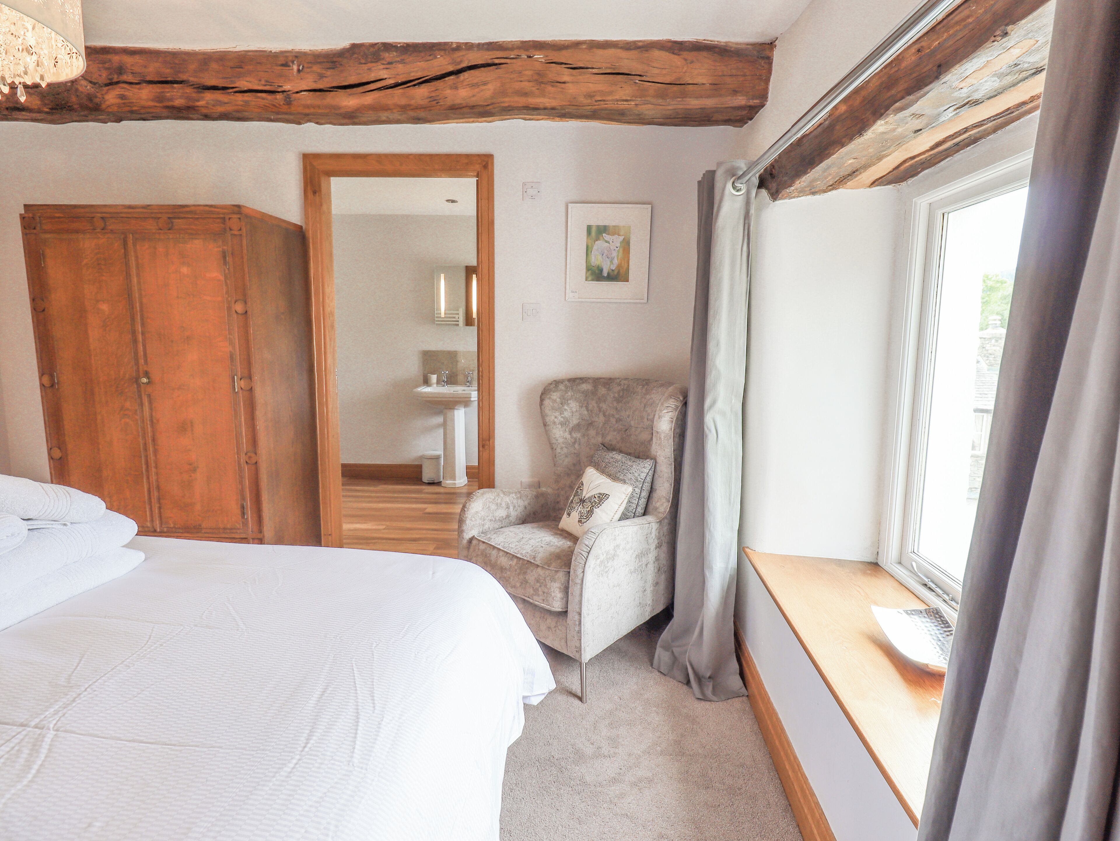 A bedroom with a bed, a chair, a wardrobe, a window, and a mirror.