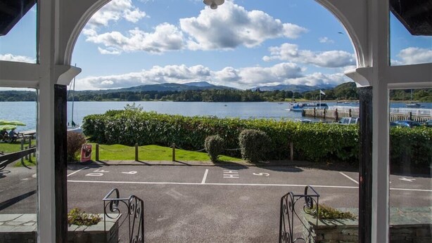 A view through a white archway with a clear sky and a body of water. - Waterside (Ambleside)