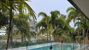 Ein Swimmingpool mit Glasbarriere, umgeben von Palmen und Blick auf eine Wohngegend.