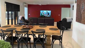 Ein modernes Wohnzimmer mit Essbereich, einem großen Flachbildfernseher und einer roten Akzentwand.