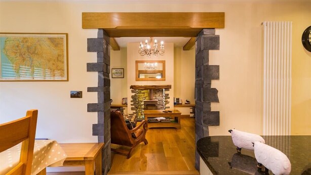 Un interior acogedor con chimenea de piedra, muebles de madera y una escultura decorativa de oveja.