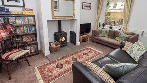 A cozy living room with a fireplace, a sofa, a bookshelf, and a television. - Number Twenty (Keswick)