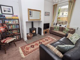 A cozy living room with a fireplace, a sofa, a bookshelf, and a television.